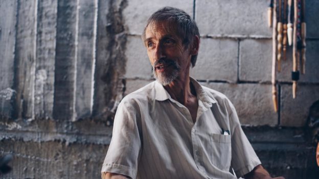 Older Syrian man in a white shirt sitting down